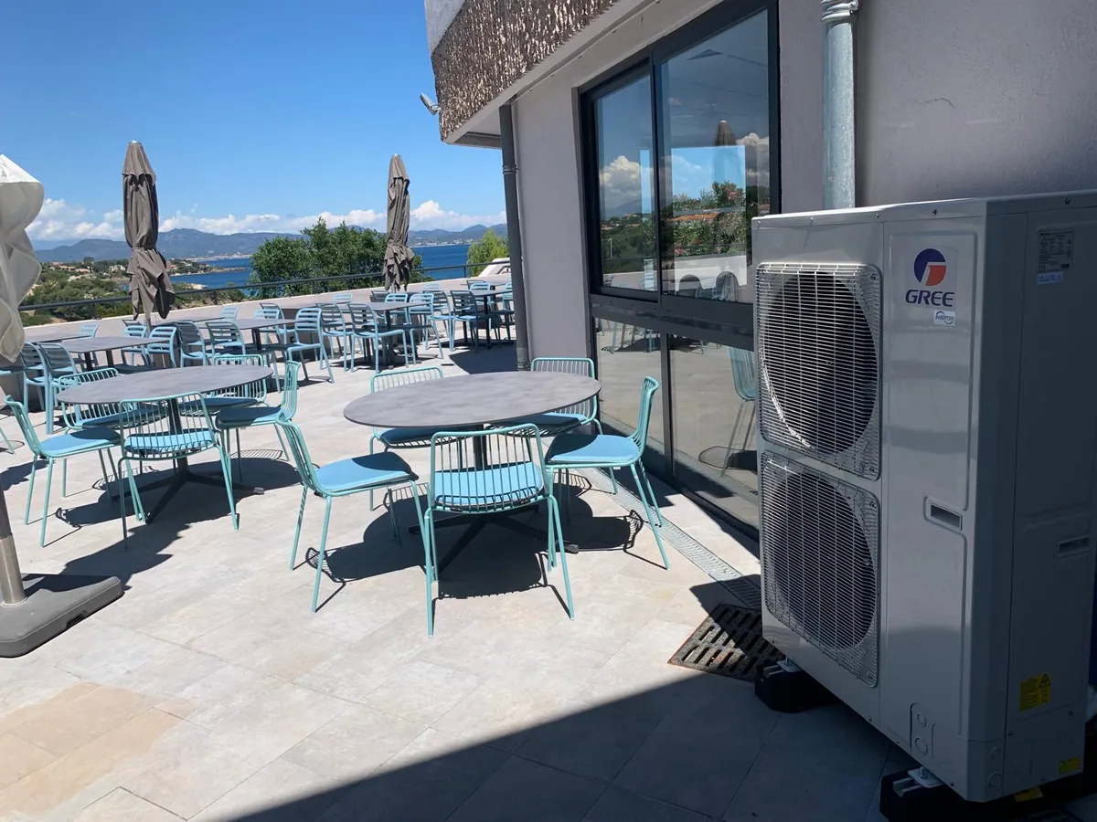 Terrasse de restaurant face à la mer, avec l'unité extérieure de climatisation posée contre la façade