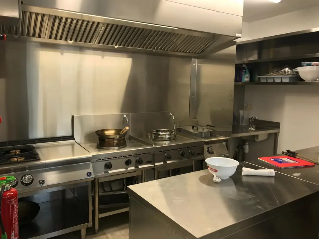 Cuisine professionnelle en inox avec piano de cuisson et hotte